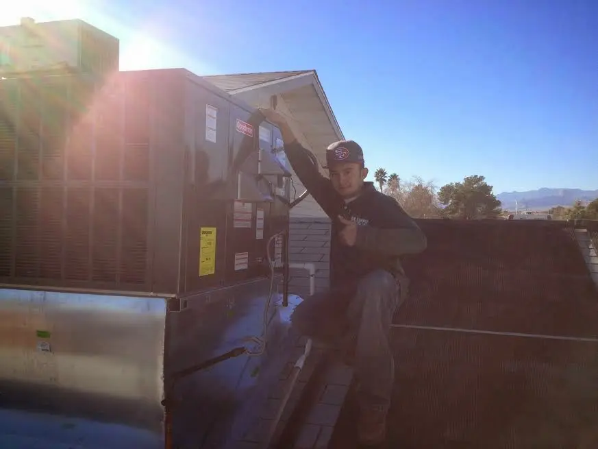 HVAC technician performing Air Duct Cleaning on a rooftop unit in Stafford